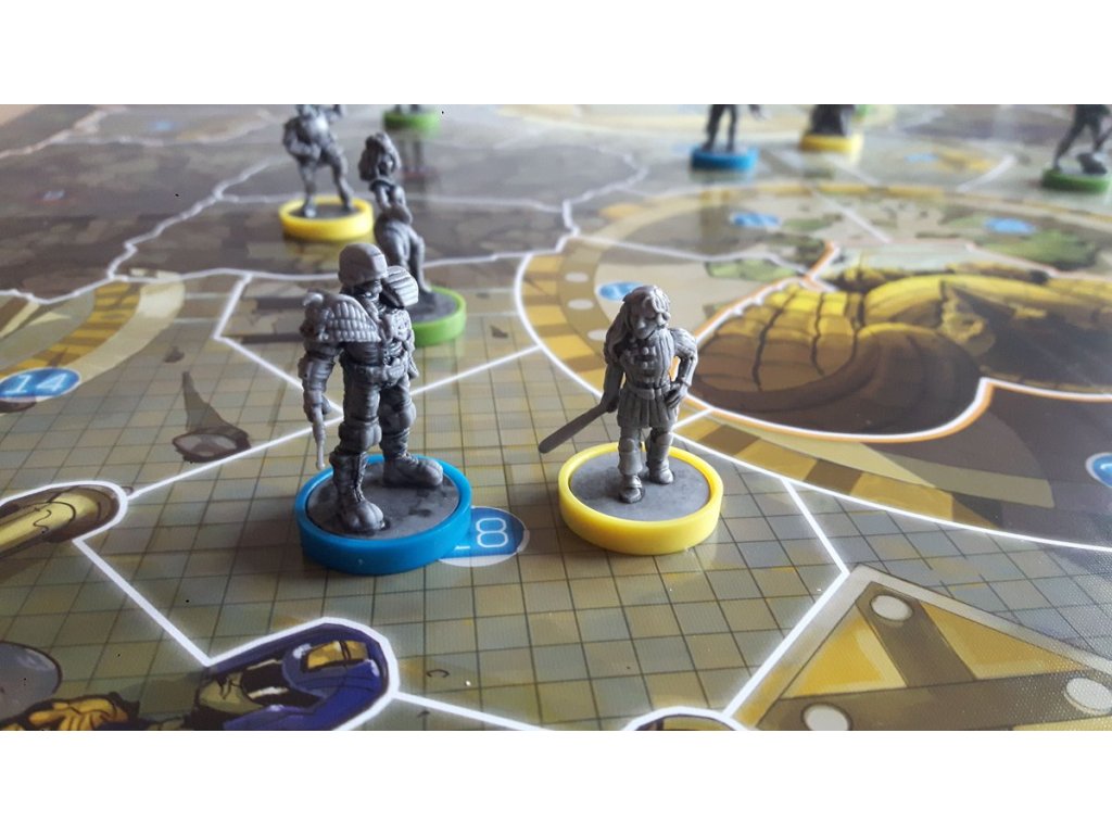 Two grey fantasy miniatures, an armored male and a female with a sword, on colored bases on a game board