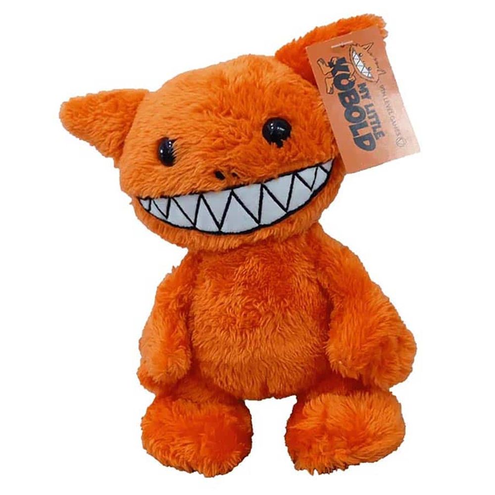 An orange furry My Little Kobold plush toy with small black eyes, a wide mouth filled with large white pointed teeth, and a tag on its right ear