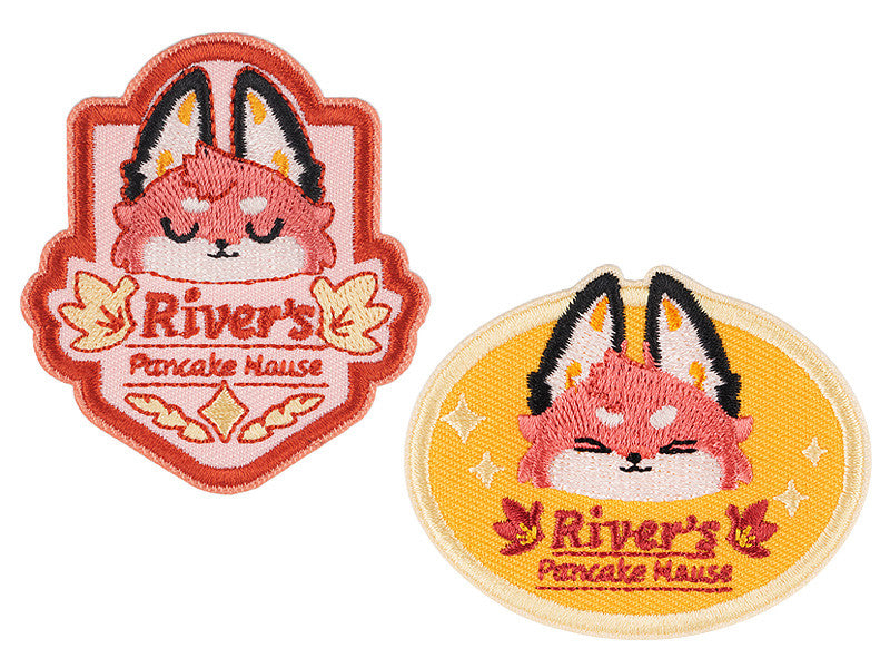 Two embroidered River's Pancake Hause patches one shield-shaped with a pink background and one oval-shaped with a yellow background