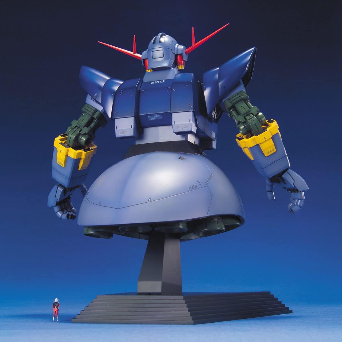 Giant blue MSN-02 Zeong mobile suit model torso displayed on a pedestal next to a tiny human figure for scale