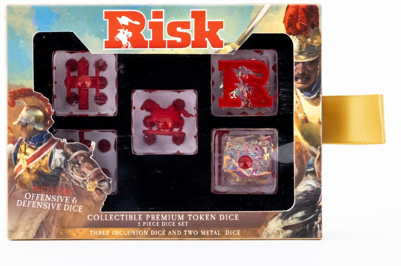 A boxed Risk dice set containing five unique collectible dice: three clear with red inclusions and two with metallic foil designs, on a background of military artwork