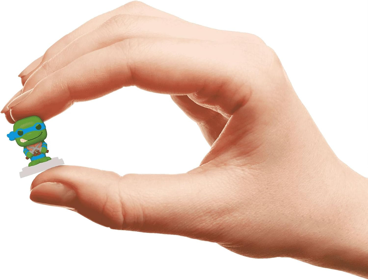 Miniature green Ninja Turtle (Leonardo) figure held between a person's index finger and thumb