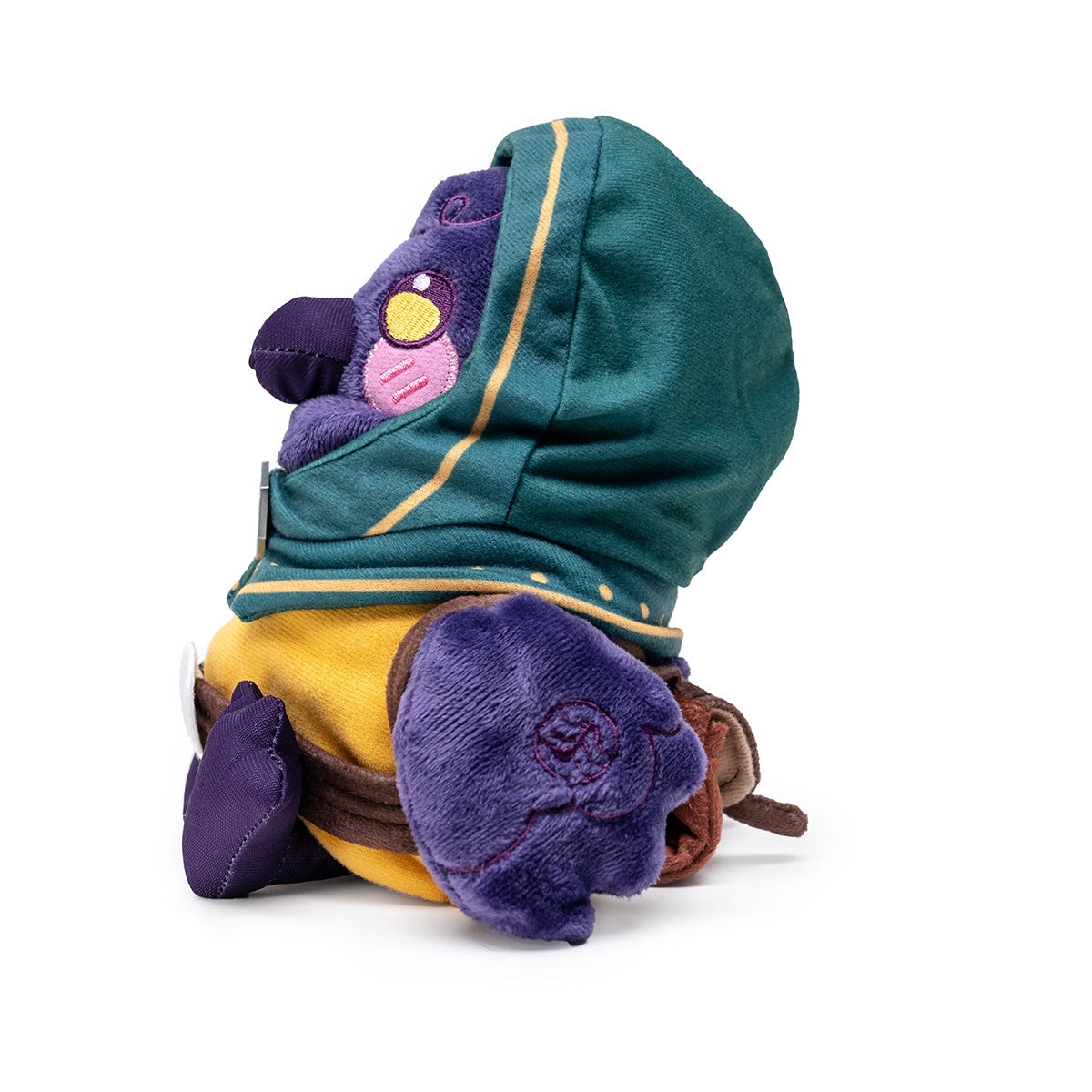 A purple character plush wearing a green hooded cloak with yellow trim and a yellow shirt, sitting, side view