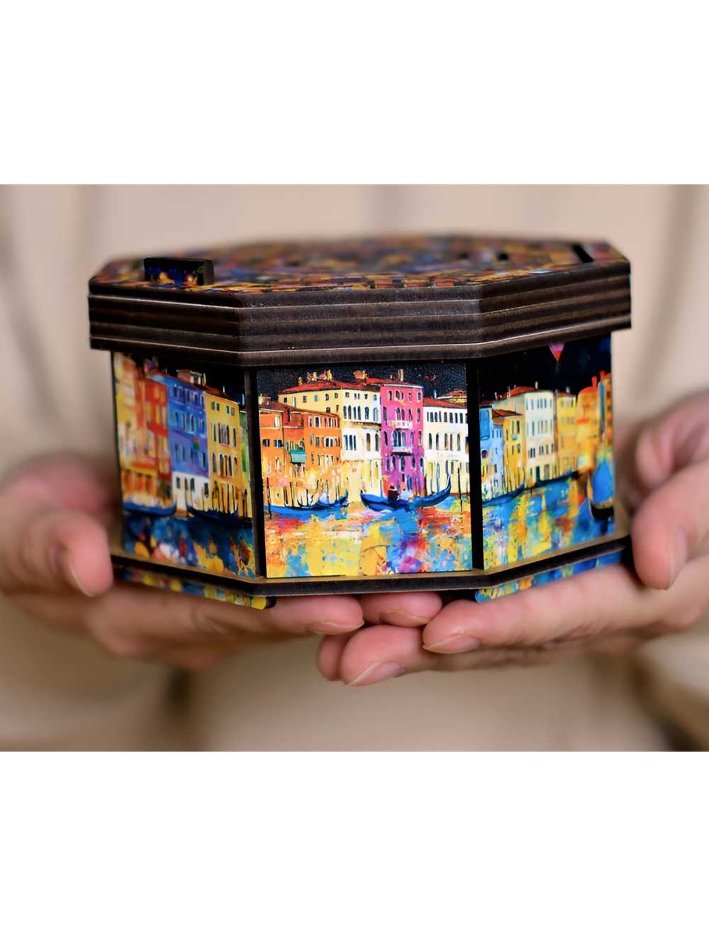 Hands hold an octagonal wooden box with colorful impressionistic art of a Venice canal and gondolas.