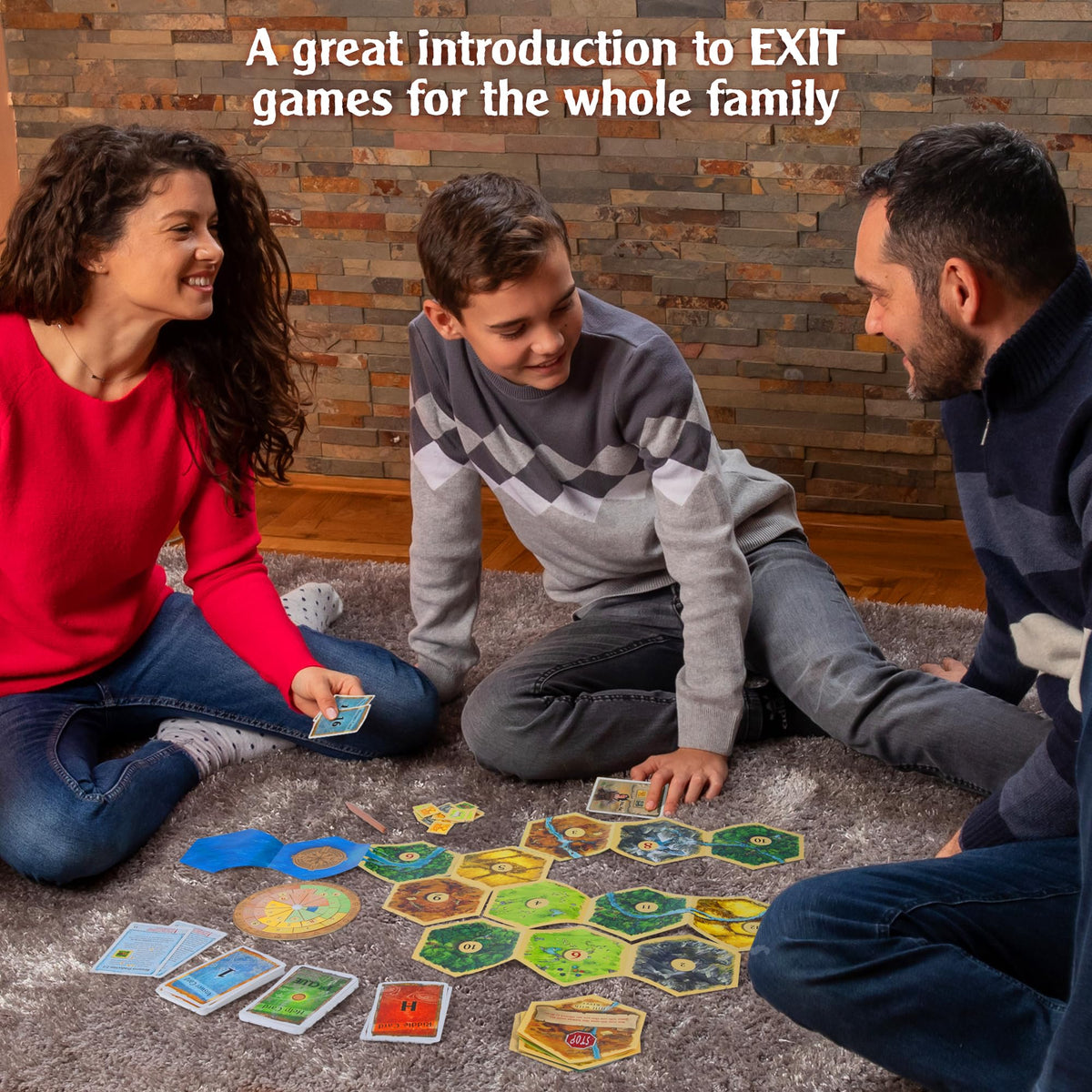 A smiling family plays Exit The Game - Adventures on Catan on a gray rug, with hexagonal landscape tiles, cards, and game pieces spread out