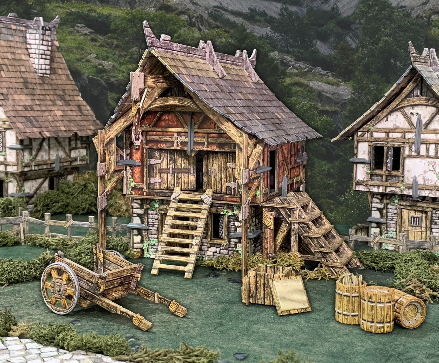 Miniature medieval diorama showing a rustic wooden workshop with stairs, a cart, barrels, and other buildings.