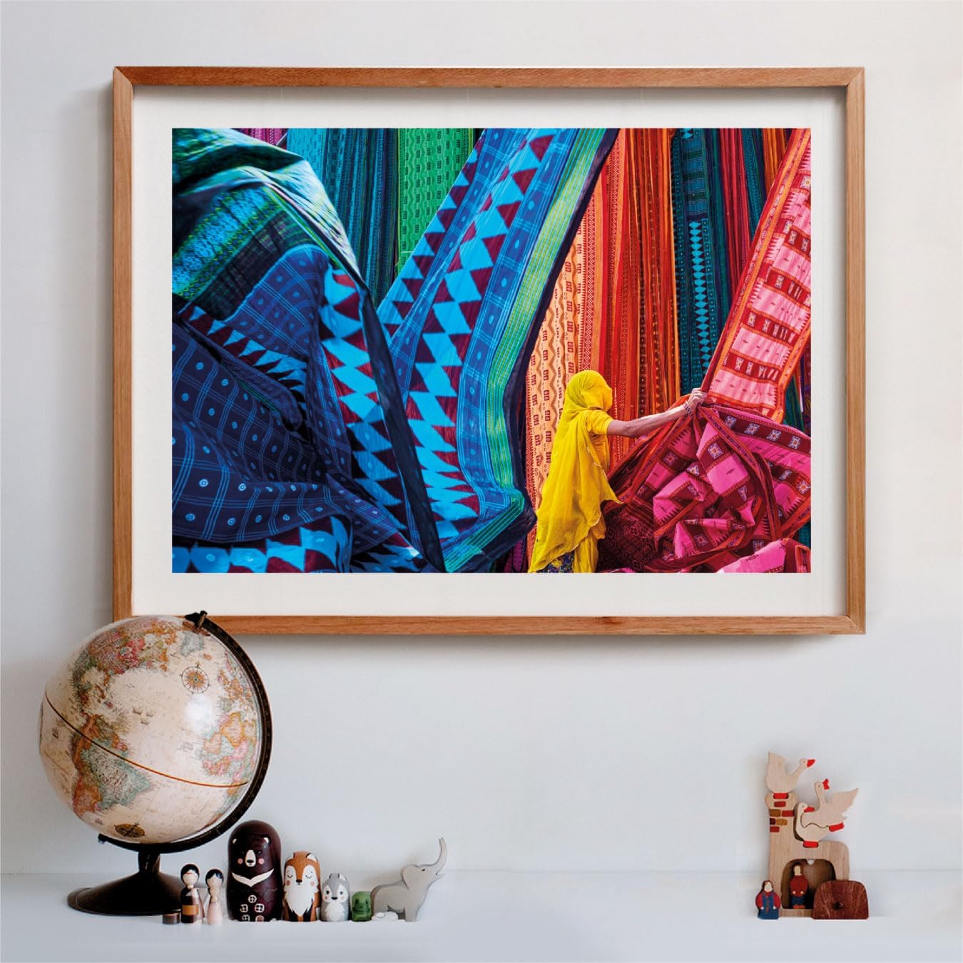 A person in yellow, wearing a head covering, examines vibrantly patterned fabrics hanging vertically