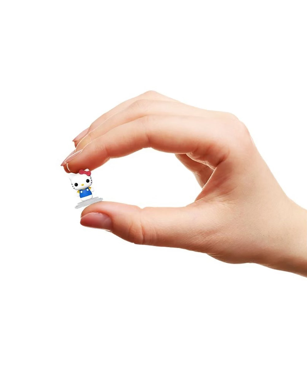 Hand holding a miniature Hello Kitty figure with a blue dress and red bow