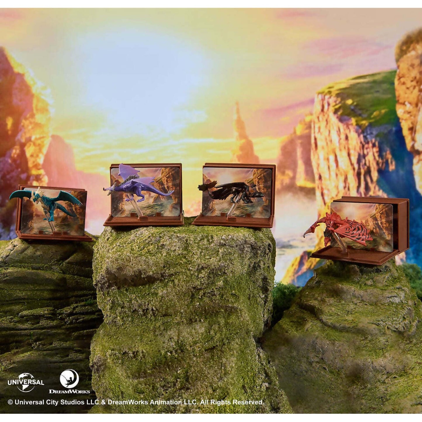 Four dragon figurines - blue, purple, black, red - in individual dioramas atop mossy cliffs against a vibrant sunset over mountains