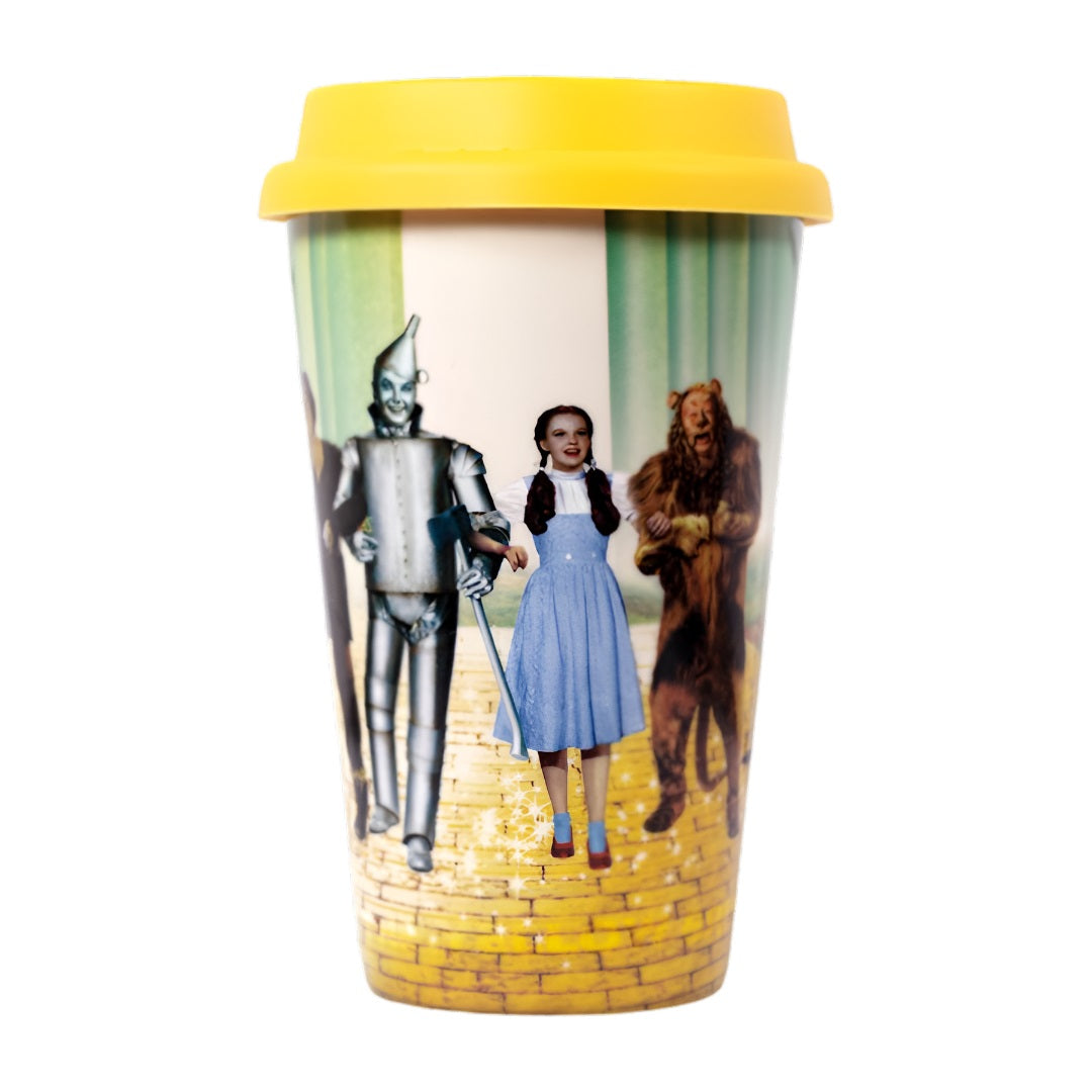 Yellow-lidded travel mug featuring Dorothy, Tin Man, and Lion walking on the Yellow Brick Road