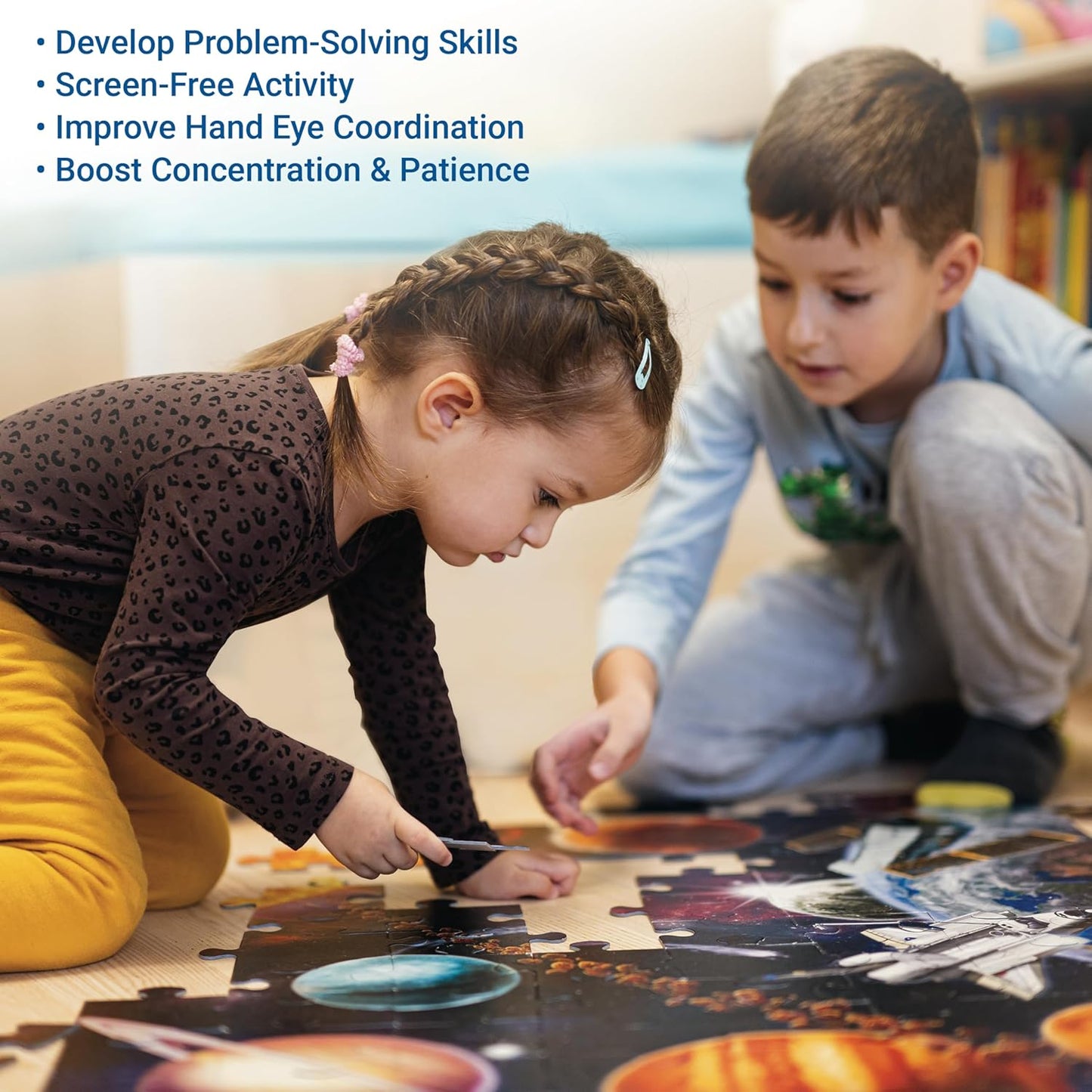 Two children kneeling on the floor, collaborating on a large space-themed jigsaw puzzle