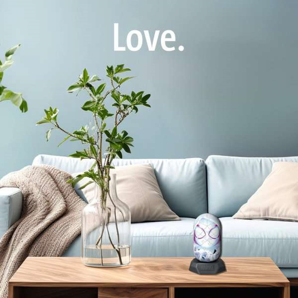 A Spider-Gwen themed device sits on a wooden coffee table in a modern living room with a blue sofa. 'Love.' is on the wall