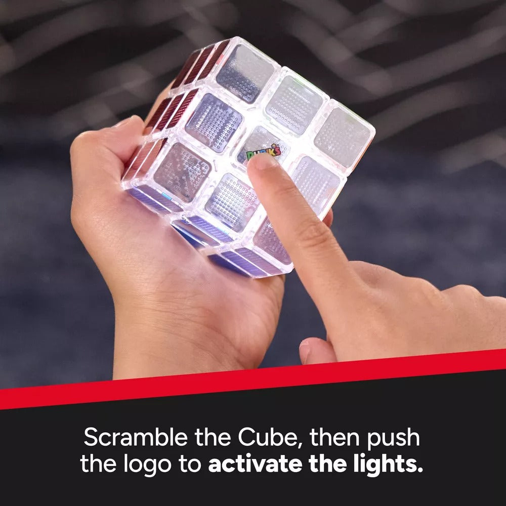 Clear, light-up Rubik's Cube held in hands, with a finger pressing the central Rubik's logo to activate its lights