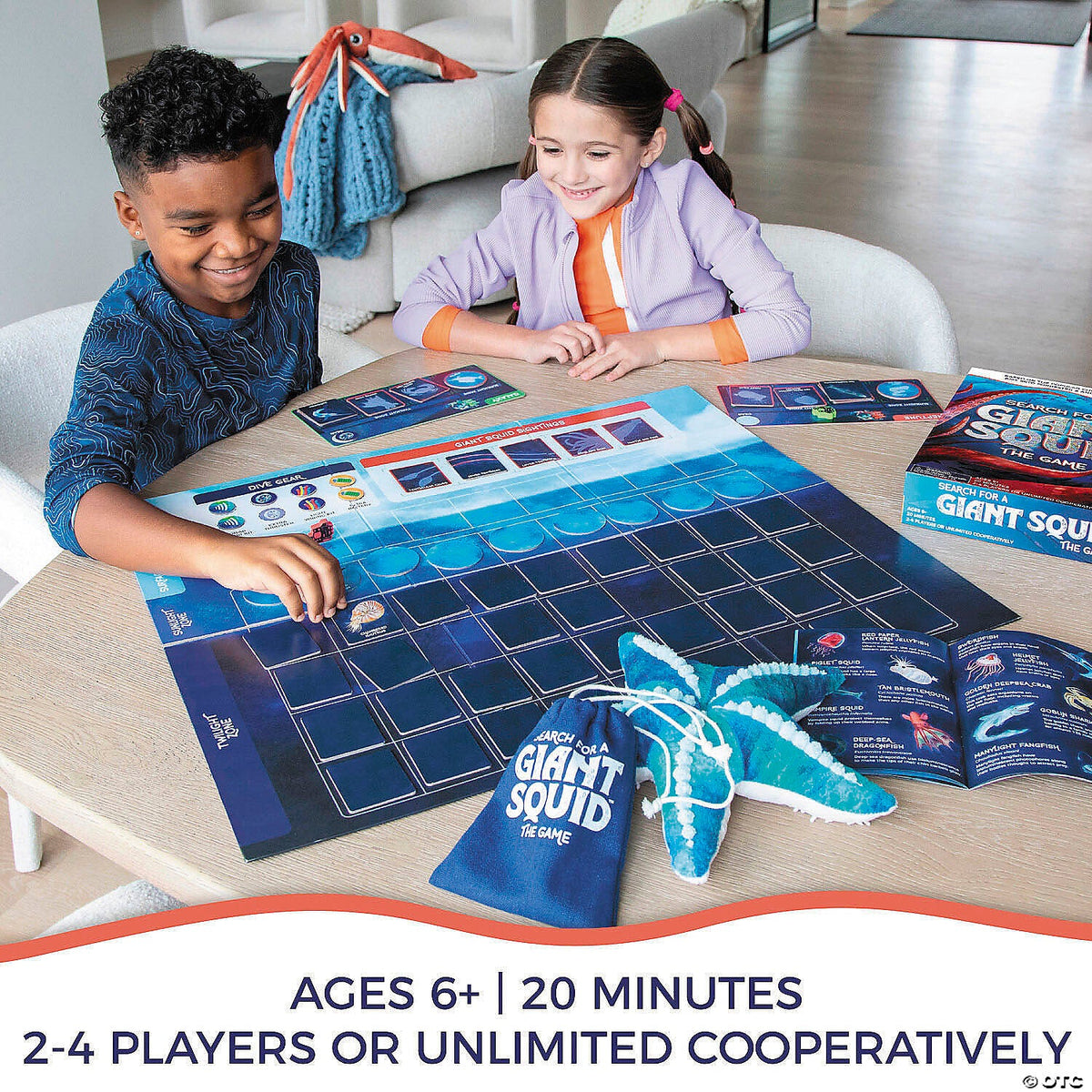 A boy and girl happily play the "Search for a Giant Squid" board game with a blue starfish prop