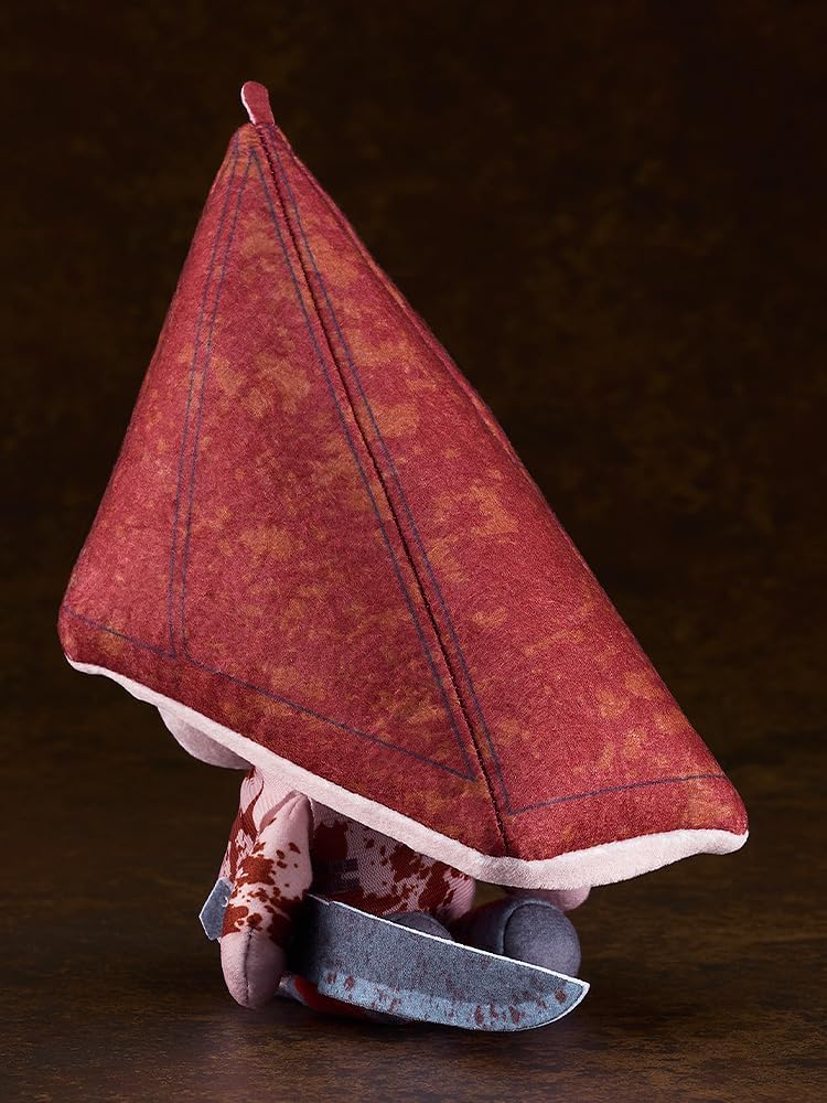 Red Pyramid Thing plush toy sits, holding a bloody cleaver. It has a textured red pyramid head and blood-splattered body