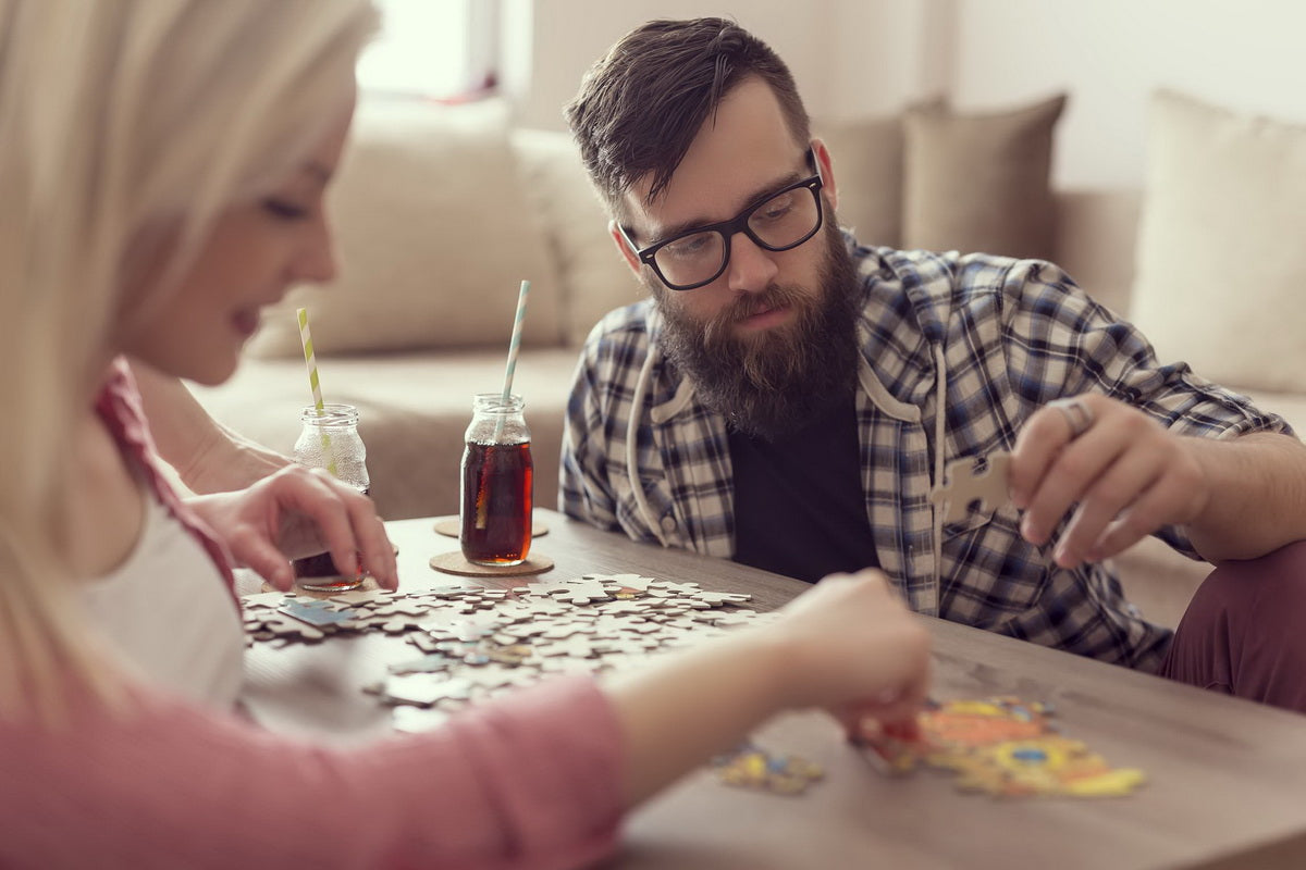 Two people doing a puzzle with drinks