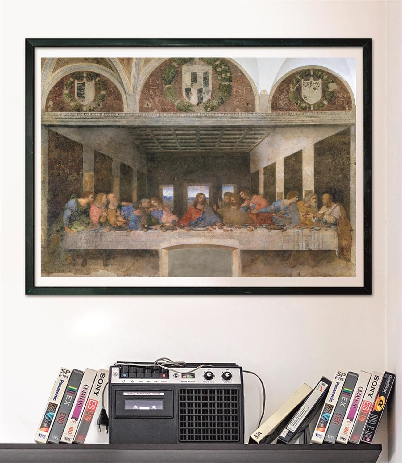 Framed "Last Supper" print with Jesus and disciples at a table, above a retro tape recorder & VHS tapes