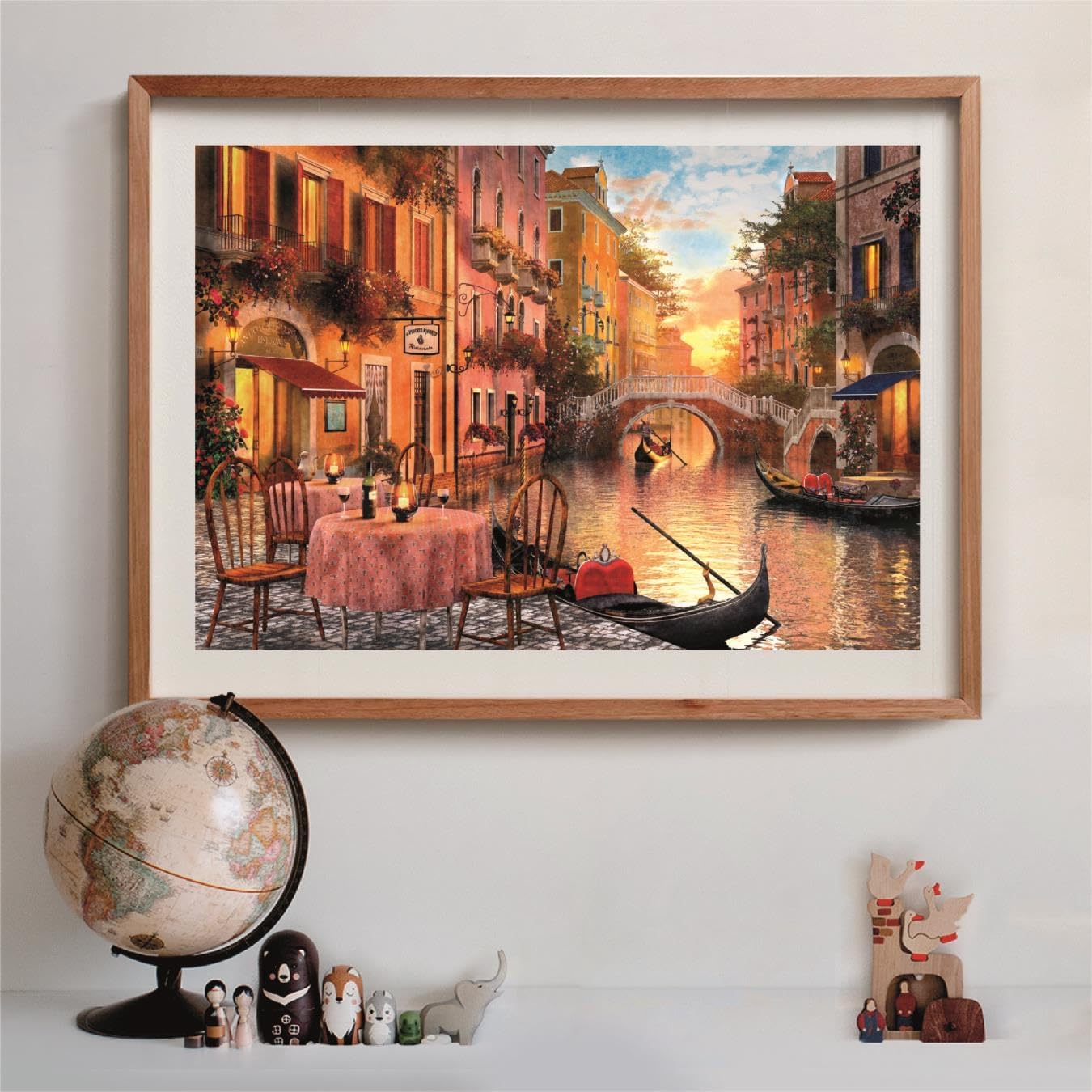 Framed painting of a vibrant Venetian canal at sunset, with gondolas, a bridge, and a quaint outdoor cafe