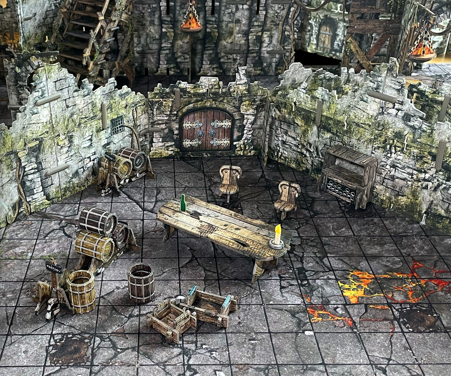 A miniature fantasy tavern setup with stone walls, wooden table, chairs, and barrels. An arched door is central, and the floor has glowing lava cracks.