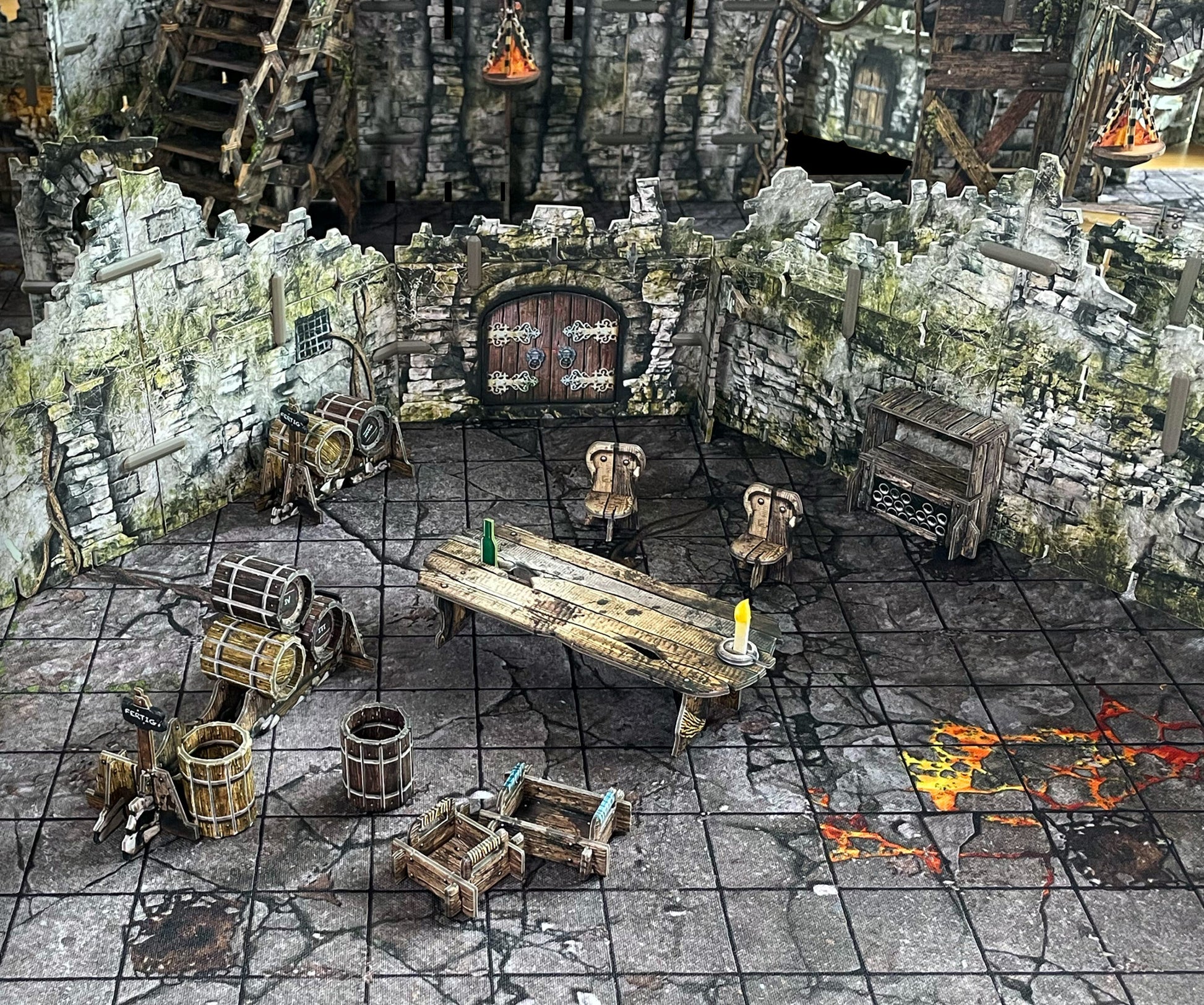 A miniature fantasy tavern setup with stone walls, wooden table, chairs, and barrels. An arched door is central, and the floor has glowing lava cracks.