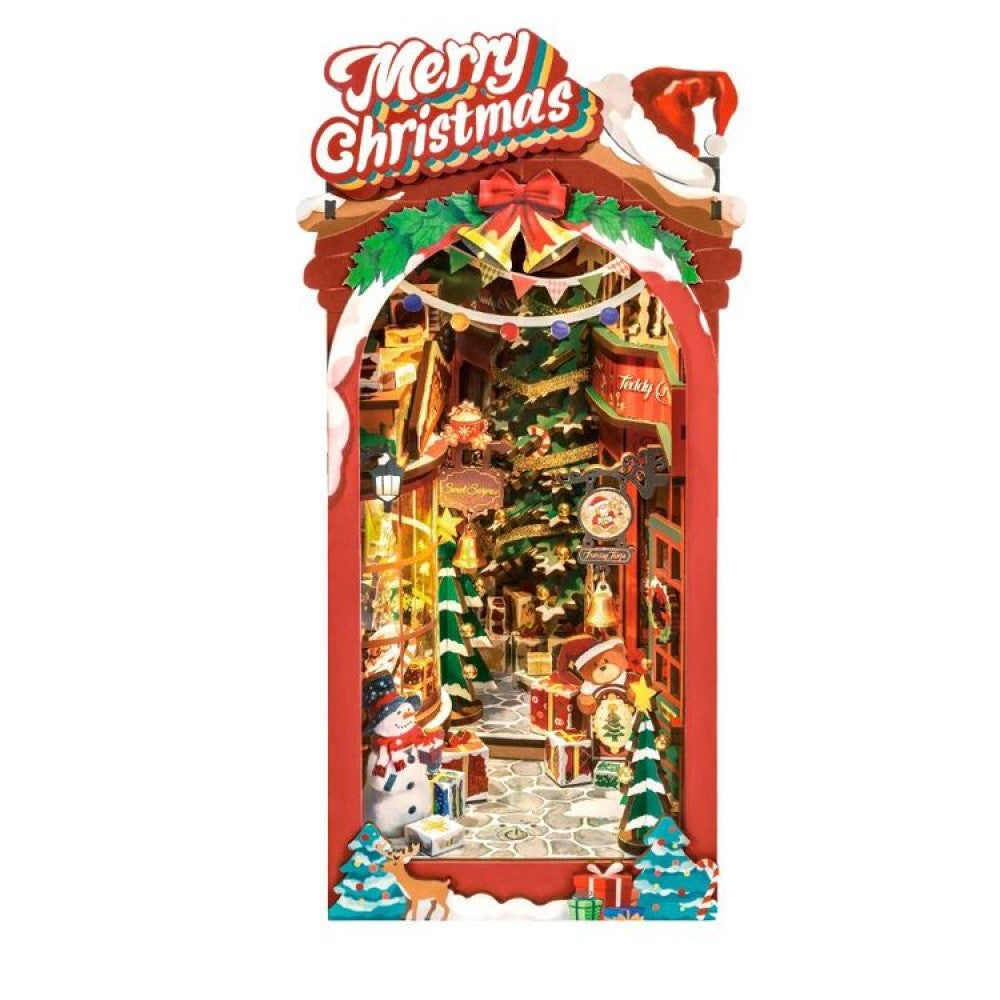 Detailed Christmas miniature diorama/book nook featuring a decorated tree, gifts and a "Merry Christmas" header
