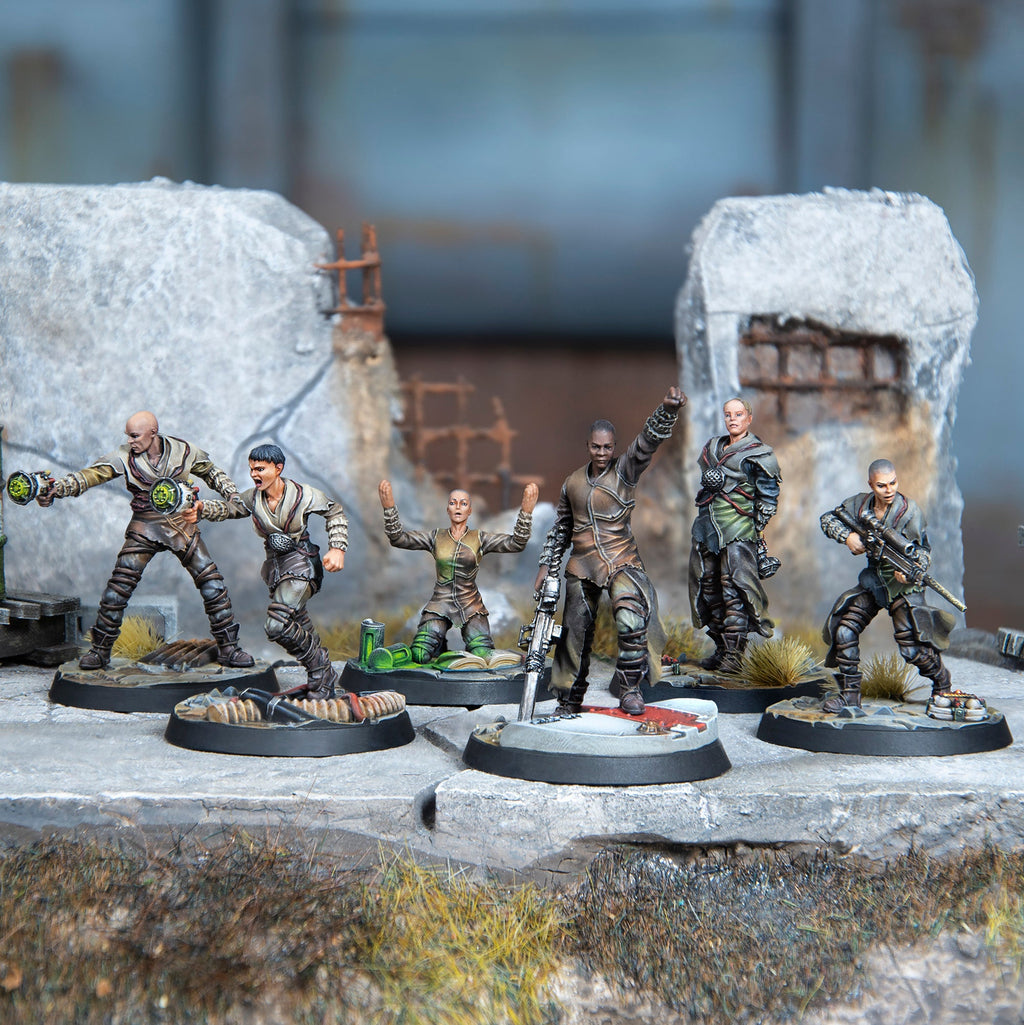 Six painted post-apocalyptic miniature figures, one with a raised fist, others with weapons, in dynamic poses on a ruined base
