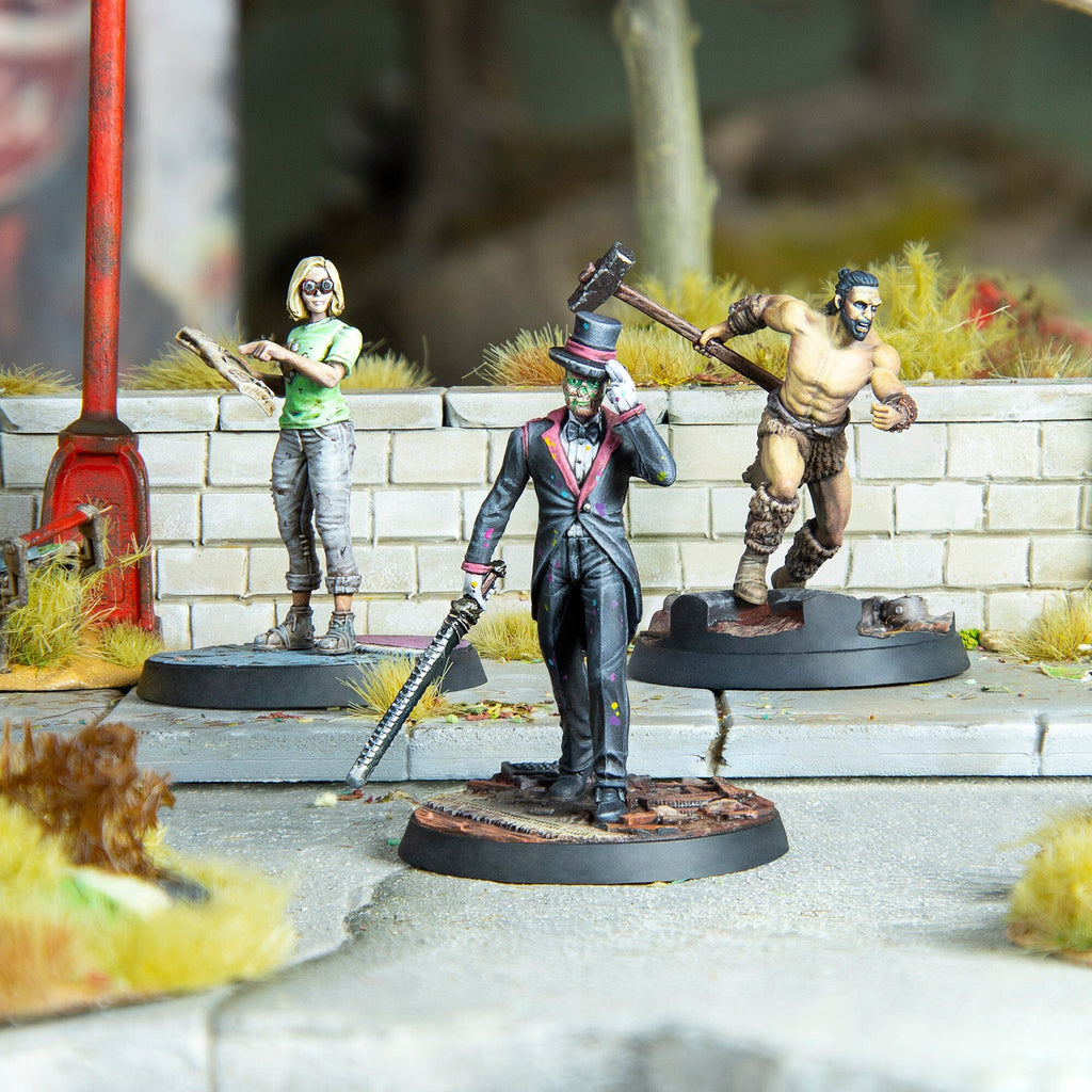 Three painted wargame miniatures: a woman with a map, a dapper man with a chainsaw sword, and a running barbarian with a hammer