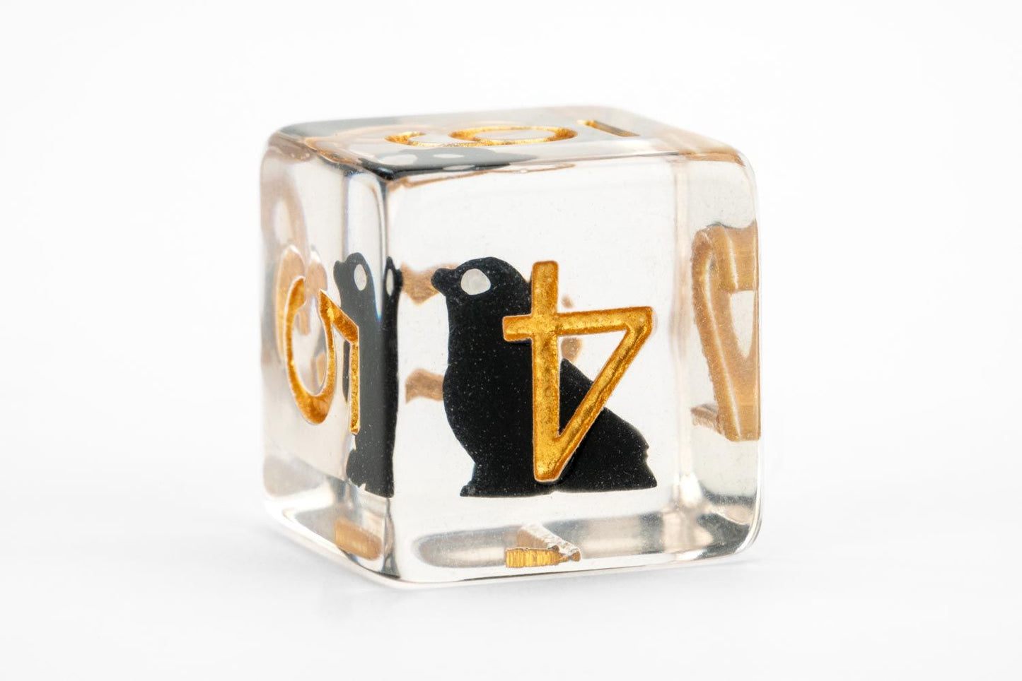Clear resin D6 die featuring an internal black animal silhouette and golden numbers/symbols on a white background