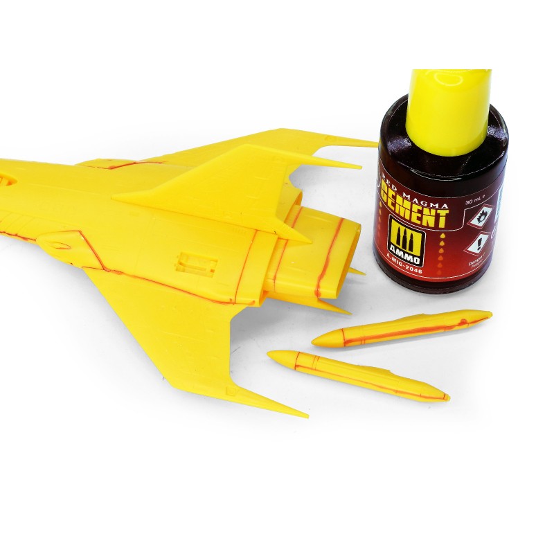 Partially built yellow plastic model jet with red panel lines, model cement, and two small yellow missile parts