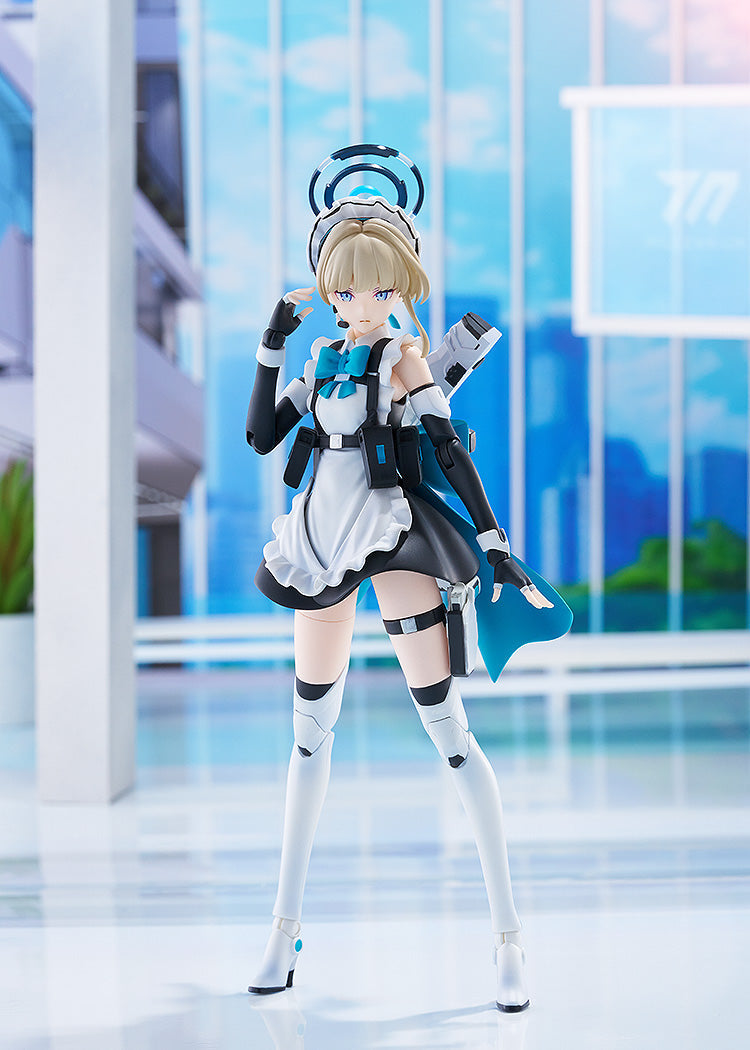 Blonde anime figure in a maid outfit with blue accents and futuristic armor, posing in a modern, light blue room