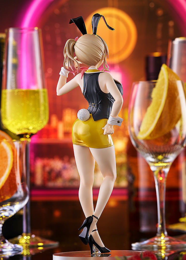 Blonde bunny girl figurine in black and yellow outfit, with black ears and white tail, looking back in a neon-lit bar