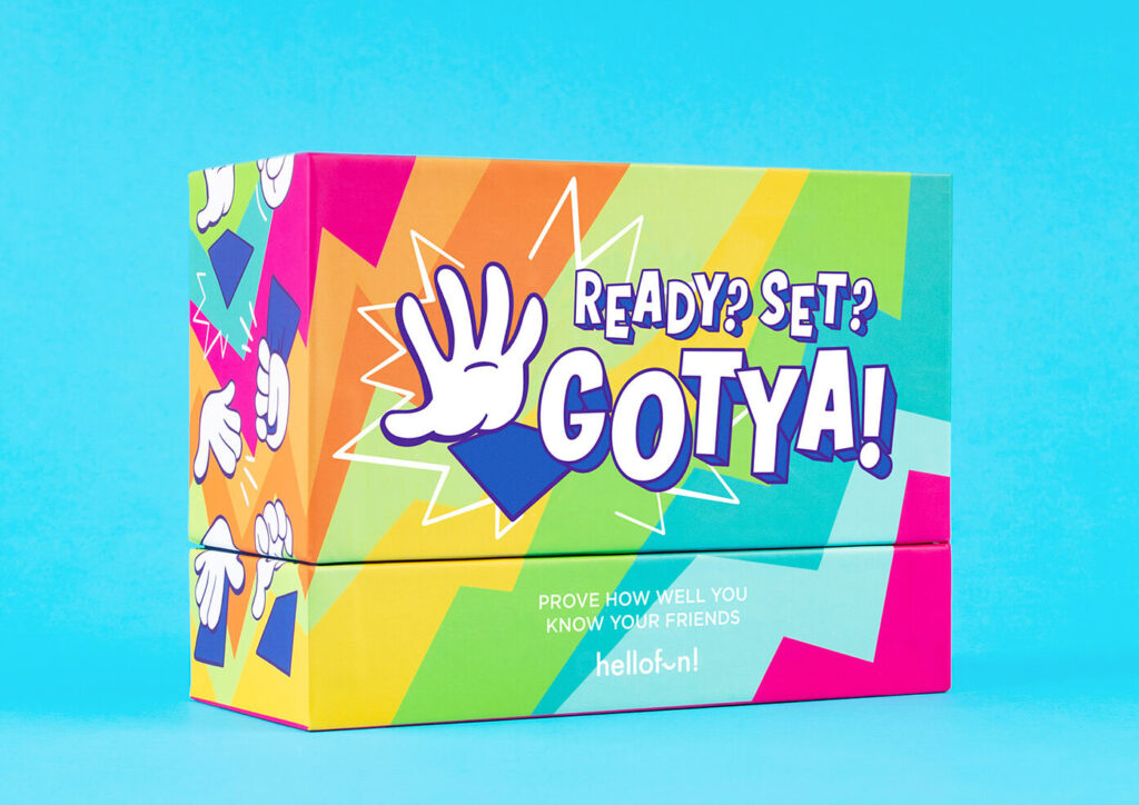 A colorful game box for 'READY? SET? GOTYA!' featuring a cartoon hand and vibrant geometric designs