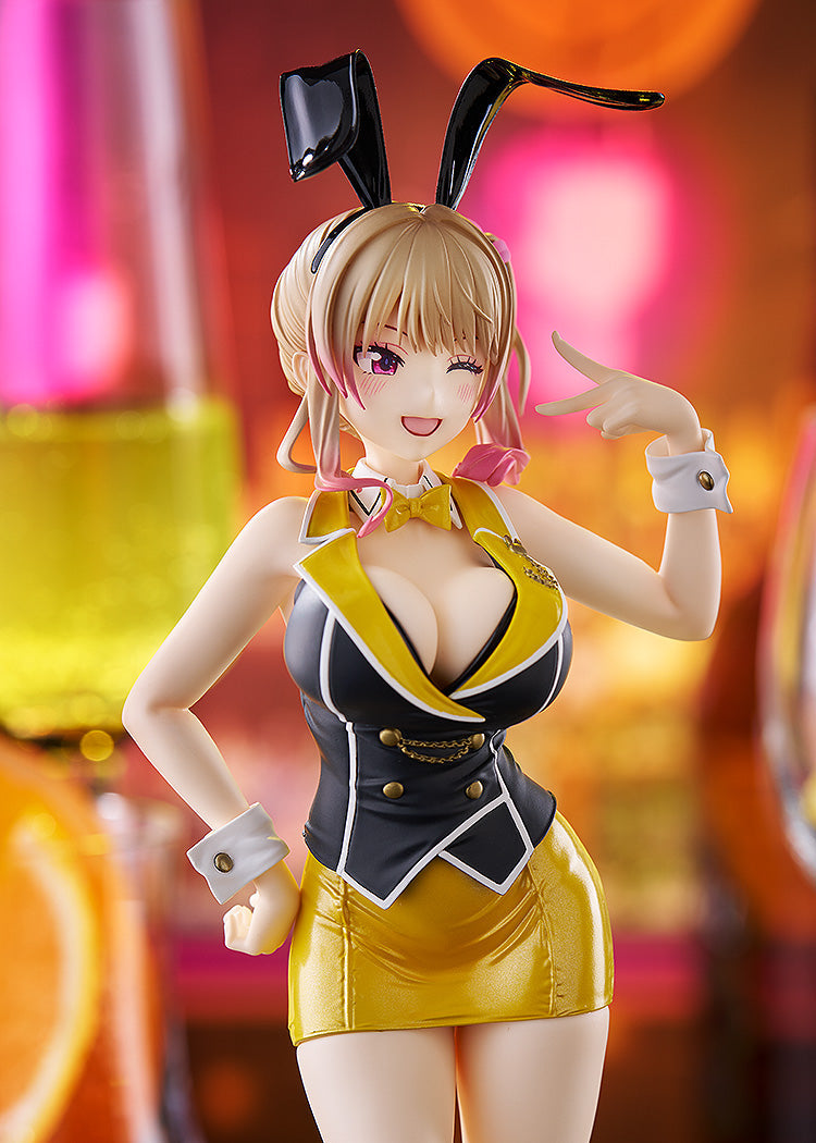 Anime figure in black and yellow bunny outfit, winking with a peace sign, against a blurred bar background