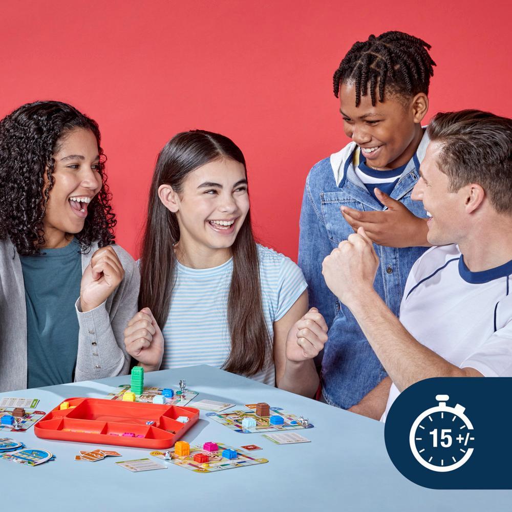 Four happy people play Monopoly GO at a table filled with colorful game pieces and cards against a red background