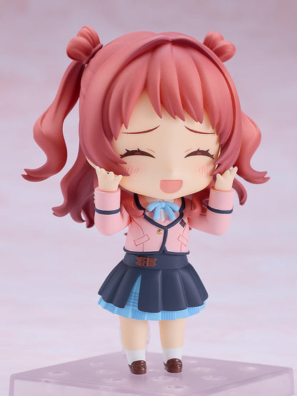 Good Smile Company Nendoroid Saki Hanami figure smiles joyfully with closed eyes and raised hands, dressed in a pink jacket and blue pleated skirt, standing on a clear display base
