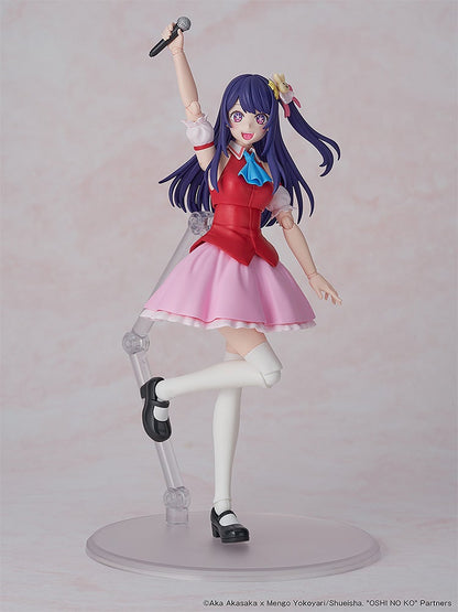 An articulated anime figure with purple hair, red top, pink skirt, holding a microphone overhead, smiling