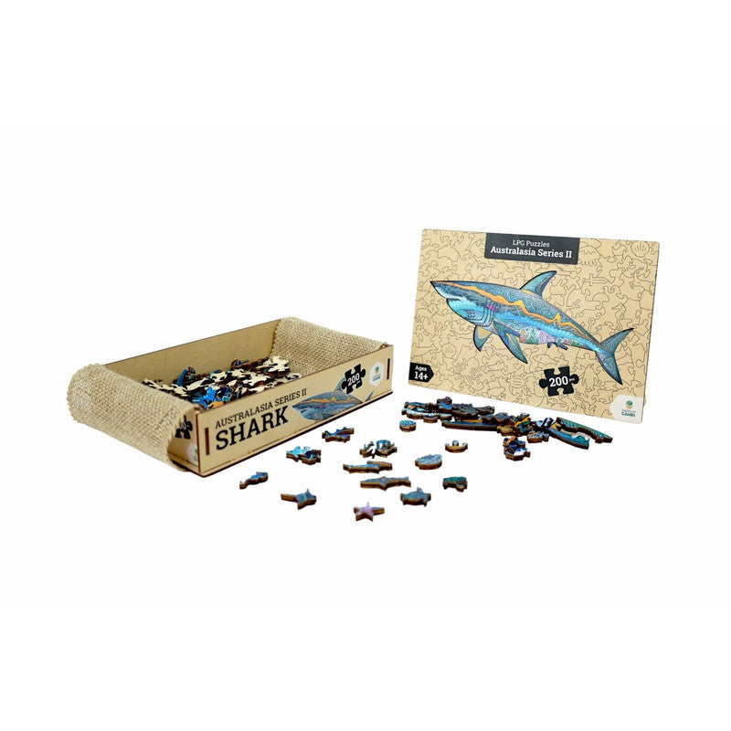 A wooden shark jigsaw puzzle with scattered pieces, a burlap tray, and the box featuring a colourful shark