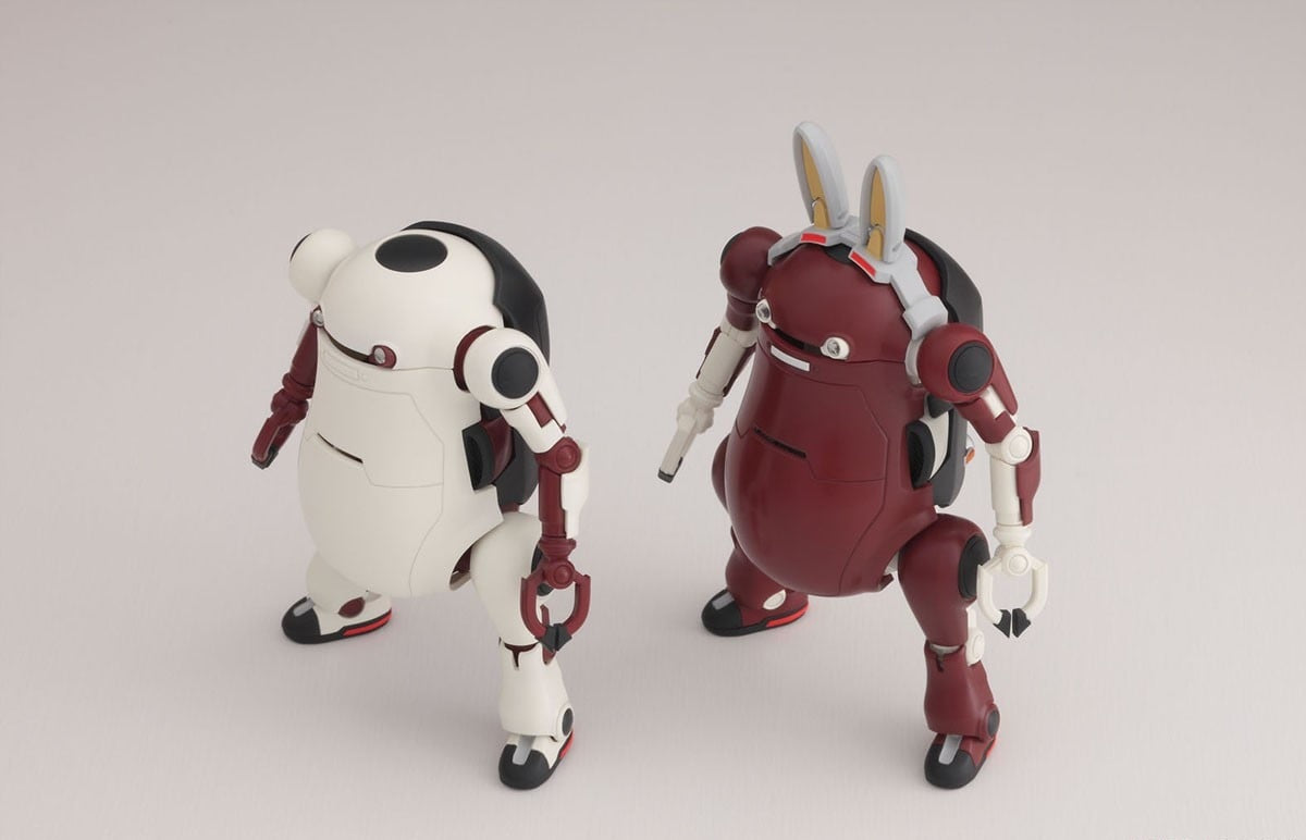 Two squat robot models: a white one and a maroon one with large rabbit ears, posing on a neutral background