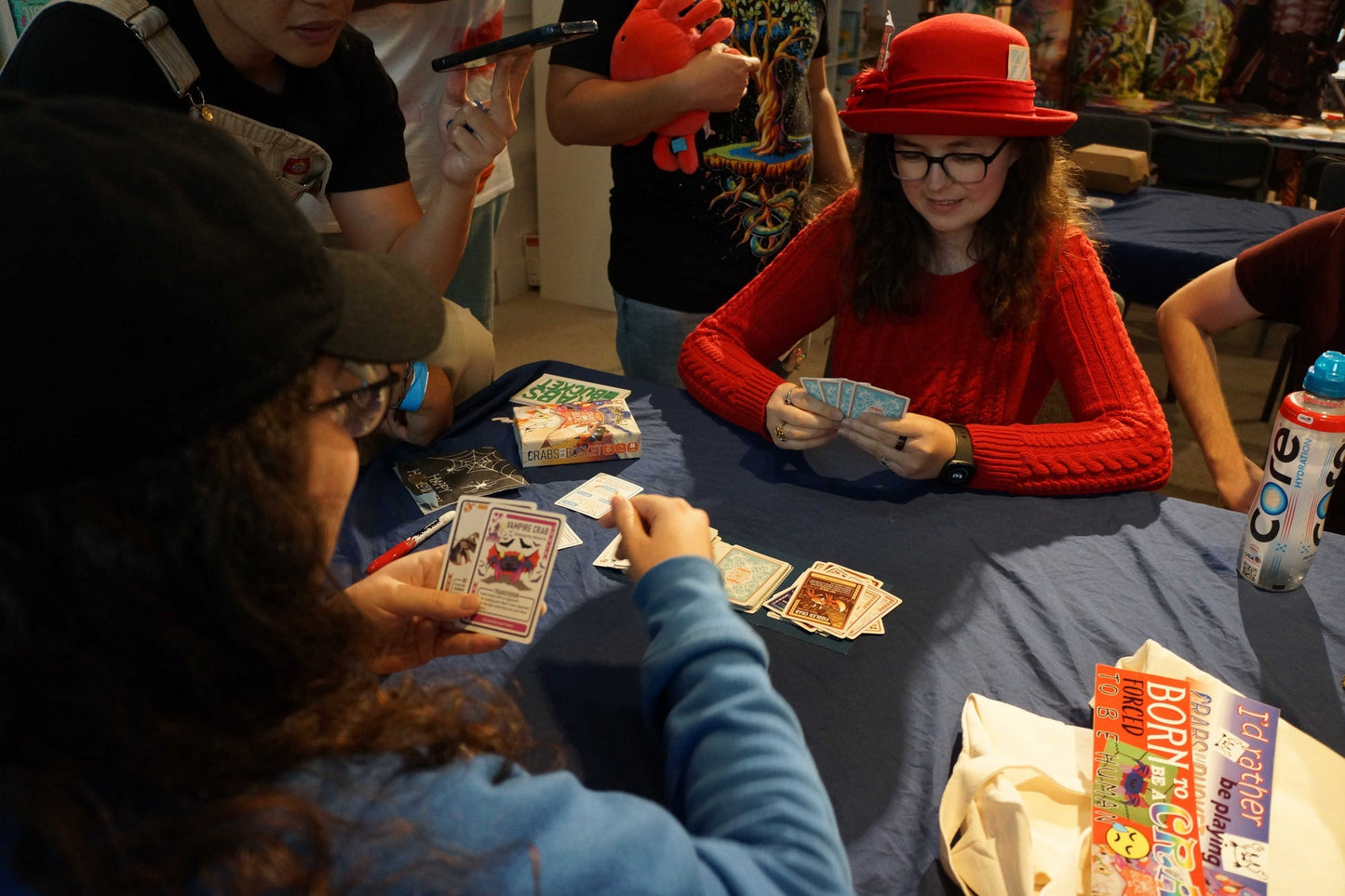 Two people play the Crabs in a Bucket card game at a blue table