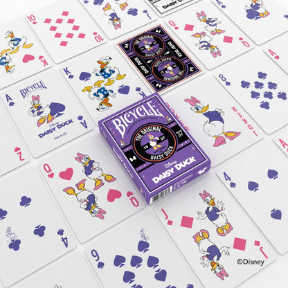 A purple Bicycle Disney Daisy Duck playing card box surrounded by many scattered cards featuring Daisy and Donald Duck artwork