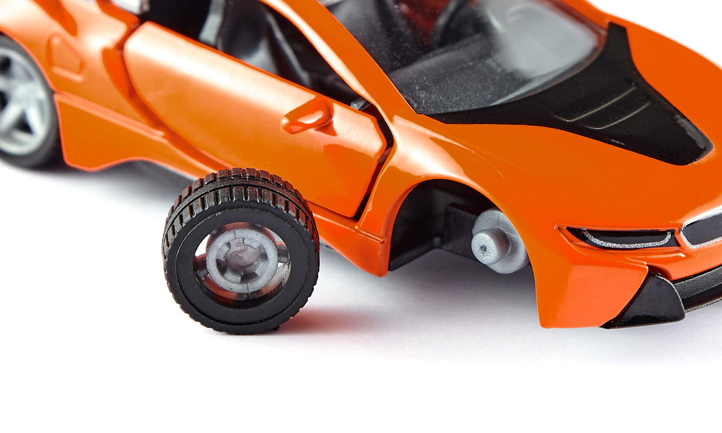 Orange toy sports car with a detached wheel resting on a white surface