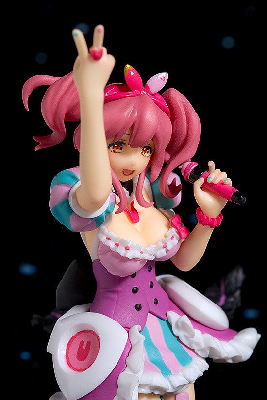 Pink-haired anime figurine with victory hand sign wearing a purple dress and microphone