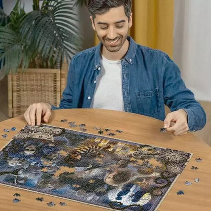 Smiling man assembling a large, colorful jigsaw puzzle on a wooden table
