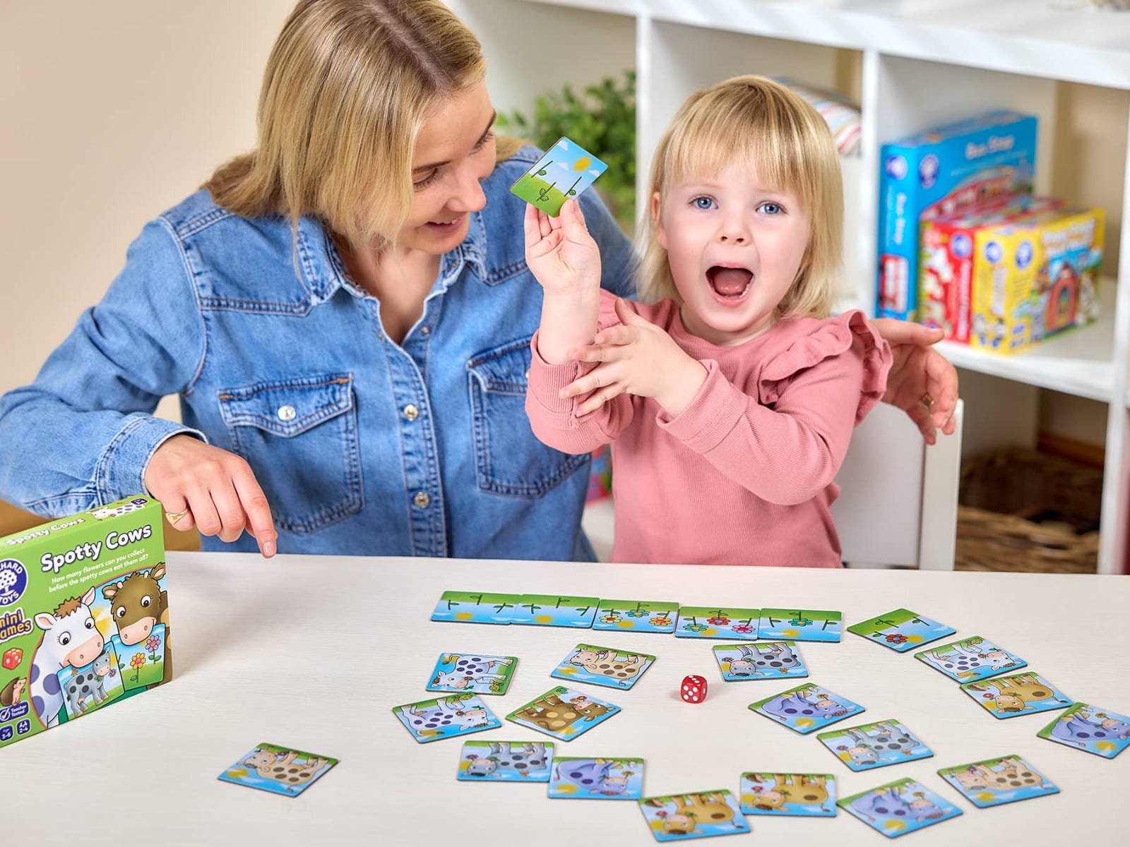 Mother and excited toddler playing the "Spotty Cows" board game with cards and a die