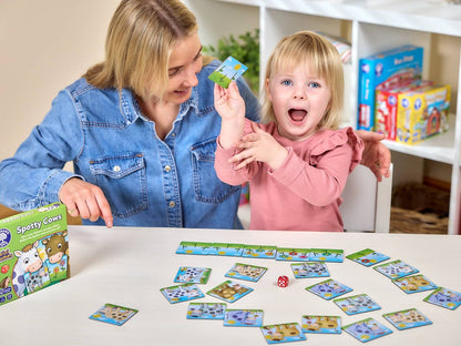 Mother and excited toddler playing the "Spotty Cows" board game with cards and a die