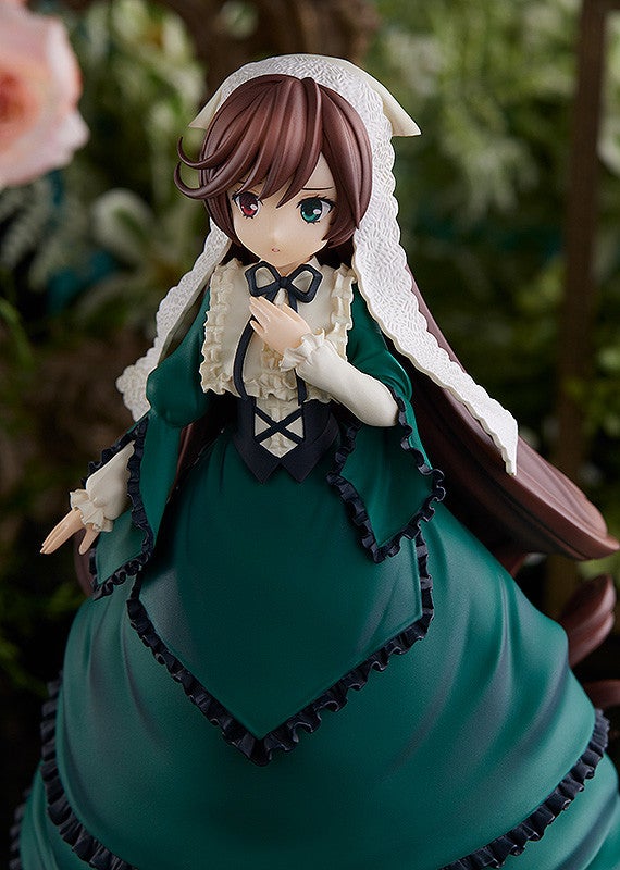 Detailed anime figure in dark green Victorian-style dress with white ruffled collar and bonnet in a garden setting