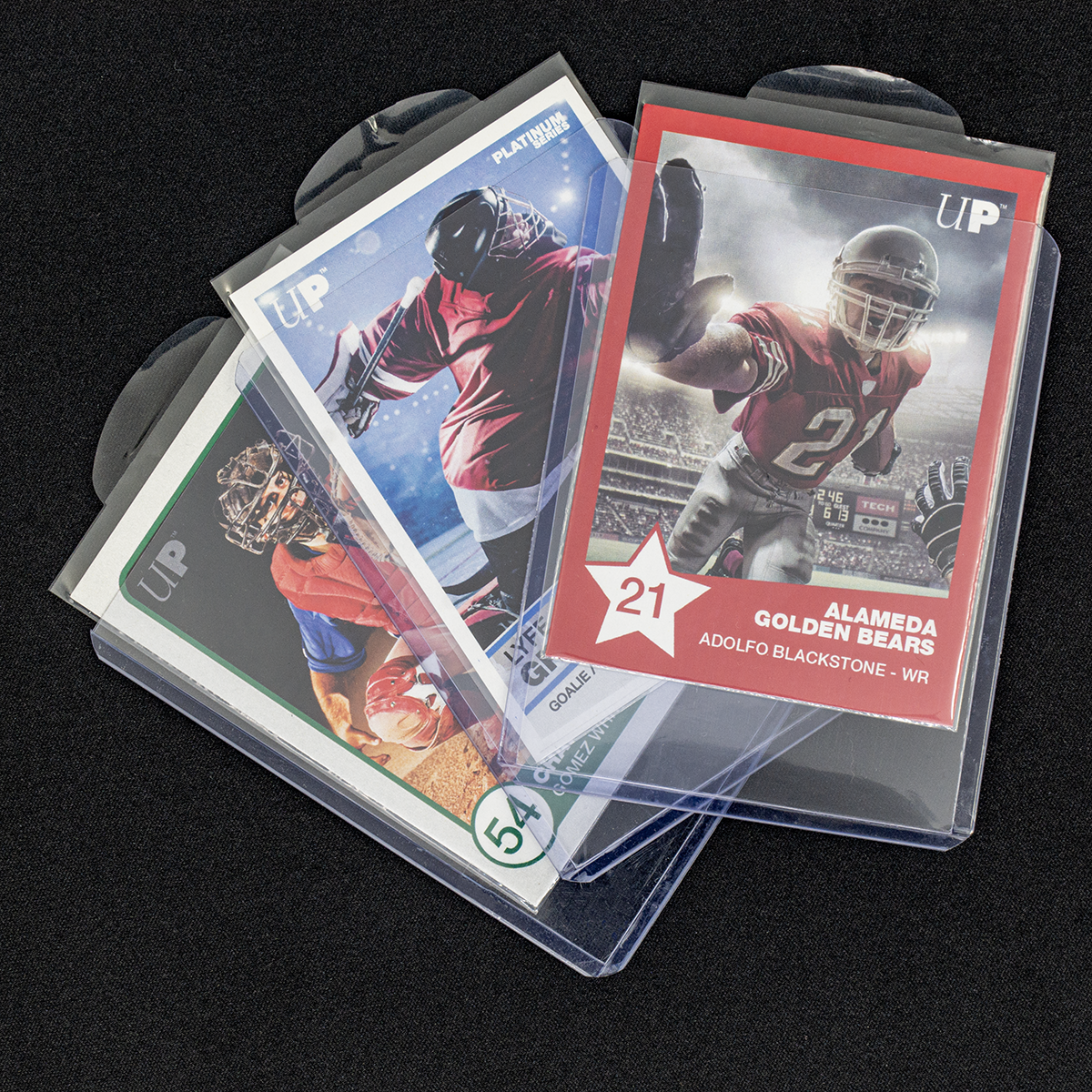 Three fanned sports cards in clear cases on a dark background, showing football, hockey, and baseball players
