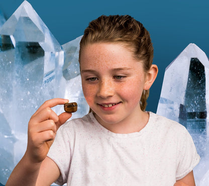 Smiling girl holds a tumbled stone (Tiger's Eye) near large quartz crystals
