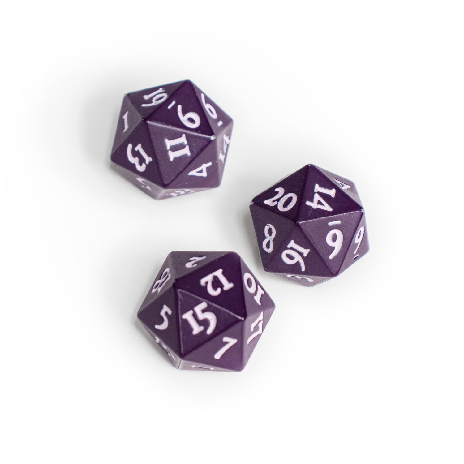 Three Midnight Plum 20-sided Ultra-Pro Vivid Heavy Metal Dice with white numbers on a white surface