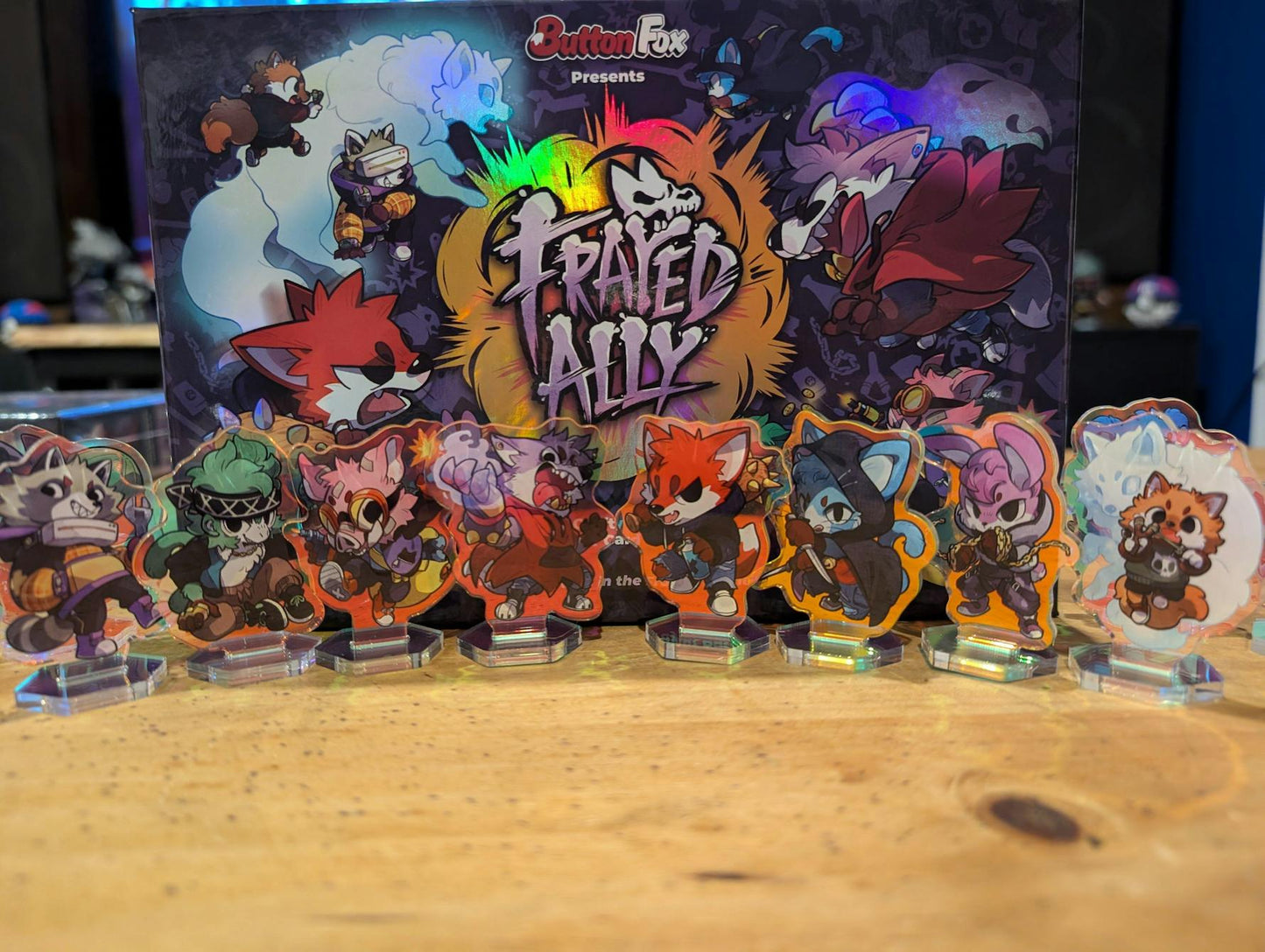 Frayed Ally board game box and a row of colorful anthropomorphic animal character acrylic standees